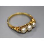 An early 20th century yellow metal and three stone split pearl set half hoop ring, with diamond chip