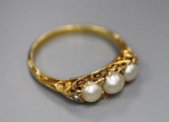 An early 20th century yellow metal and three stone split pearl set half hoop ring, with diamond chip