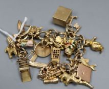 A yellow metal charm bracelet, hung with twenty seven assorted charms, including 9ct phone box, Toby