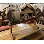 Two tan leather saddles on a pine saddle stand