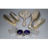 A silver mounted mirror, four silver brushes, a pair of toastracks and a pair of silver salts.