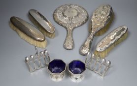 A silver mounted mirror, four silver brushes, a pair of toastracks and a pair of silver salts.