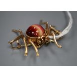 A yellow metal and chatoyant cabochon gem set spider brooch, 35mm, gross 10 grams.