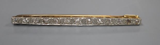 An early 20th century 15ct, plat and graduated thirteen stone diamond set bar brooch, 57mm, gross