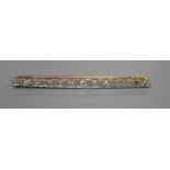 An early 20th century 15ct, plat and graduated thirteen stone diamond set bar brooch, 57mm, gross