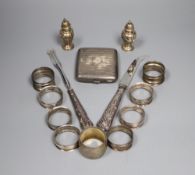 Nine assorted silver napkin rings, a pair of silver pepperettes, a silver cigarette case and pair of