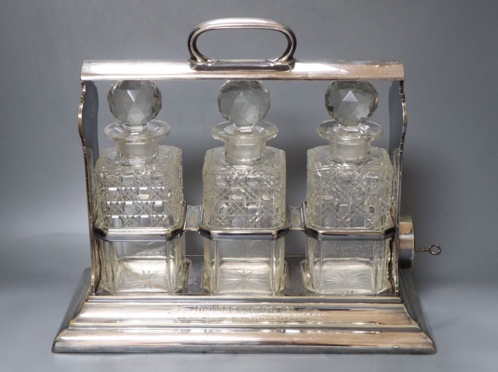 A silver plate three bottle tantalus, width 38cmCONDITION: Two decanters each with a chip to the