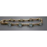 A modern 585 yellow metal and nine stone oval cut blue topaz set bracelet, 21.5cm, gross 16.8