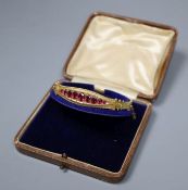 A cased Edwardian 9ct gold and graduated red stone doublet set hinged bracelet, gross 9 grams.