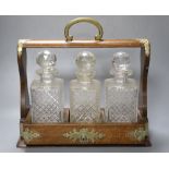 A Victorian / Edwardian oak three bottle tantalus, unlocked, no key, 35cm wide