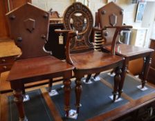 A 19th century carved oak hall elbow chair, together with two similar mahogany hall chairs