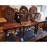 A 19th century carved oak hall elbow chair, together with two similar mahogany hall chairs