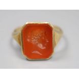 A continental yellow metal and intaglio carnelian set signet ring, carved with head of a lady to