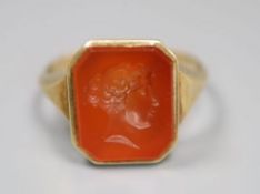 A continental yellow metal and intaglio carnelian set signet ring, carved with head of a lady to