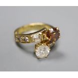 A modern yellow metal and two colour diamond two stone crossover ring, with baguette and round cut
