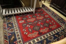 A Caucasian design red ground carpet, 285 x 194cmCONDITION: Heavily worn and faded in places,