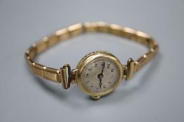 A lady's 9ct gold manual wind wrist watch, on a gold plated bracelet, gross 14.3 grams.