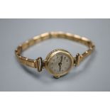 A lady's 9ct gold manual wind wrist watch, on a gold plated bracelet, gross 14.3 grams.