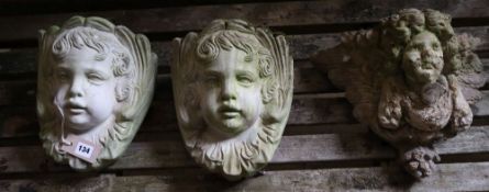 Three reconstituted stone cherub garden wall appliques, tallest 32cm