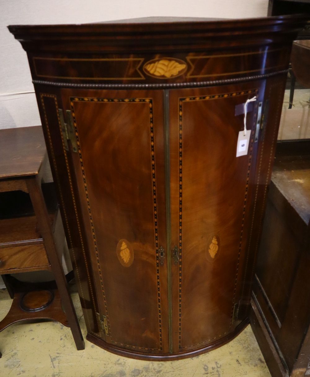 A George III inlaid mahogany bow-fronted hanging corner cupboard, having geometric line and shell