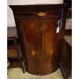 A George III inlaid mahogany bow-fronted hanging corner cupboard, having geometric line and shell