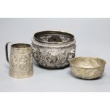 A 19th century Indian white metal embossed sugar bowl, a christening mug and a small brass bowl. (