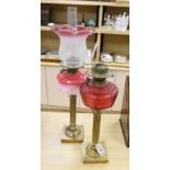 A brass column oil lamp with cranberry glass reservoir and frilled frosted and pink glass shade