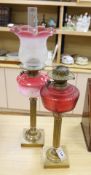 A brass column oil lamp with cranberry glass reservoir and frilled frosted and pink glass shade