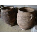 A pair of three-handled terracotta oil jars, each with ribbed sides and narrow foot, height 100cm (