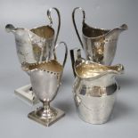 Four silver helmet-shaped cream jugs, three George III, one late Victorian, variously pricked and