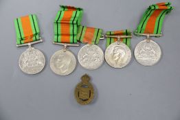 Seven WWII Defence medals and two cap badgesCONDITION: No names/numbers on medals, all blank
