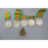 Seven WWII Defence medals and two cap badgesCONDITION: No names/numbers on medals, all blank