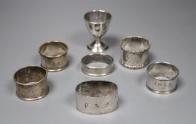 A pair of silver napkin rings, four other silver napkin rings and a small plated trophy cup.