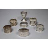 A pair of silver napkin rings, four other silver napkin rings and a small plated trophy cup.