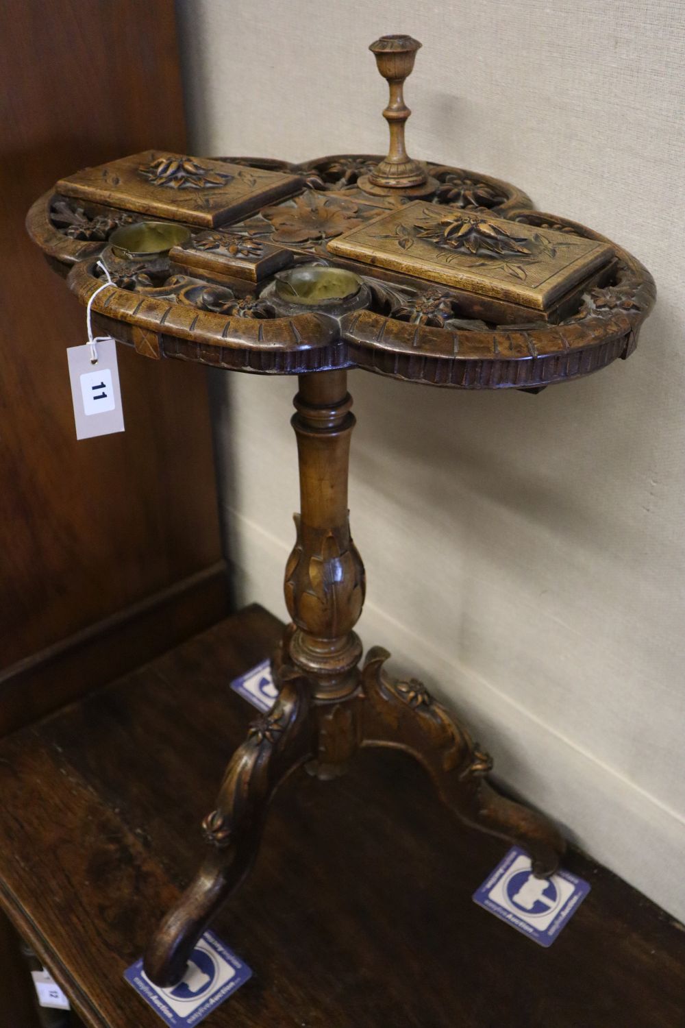 A 19th century Alpine carved fruitwood smoker's compendium, the quatrefoil top pierced and carved