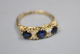 An 18ct, three stone sapphire and four stone diamond set dress ring, with carved setting, size O,