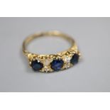 An 18ct, three stone sapphire and four stone diamond set dress ring, with carved setting, size O,