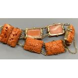 An early 20th century yellow metal seven stone coral panel set bracelet, carved with flowers, with