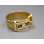 A late Victorian 18ct gold, three stone sapphire and diamond set buckle ring, size O/P, gross 5.1