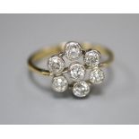 A 750 yellow metal and seven stone diamond cluster flower head ring, size L, gross 3.3 grams.