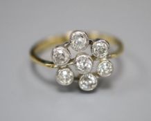 A 750 yellow metal and seven stone diamond cluster flower head ring, size L, gross 3.3 grams.