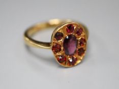 An 18ct and nine stone garnet oval cluster ring, size N, gross 4.4 grams.