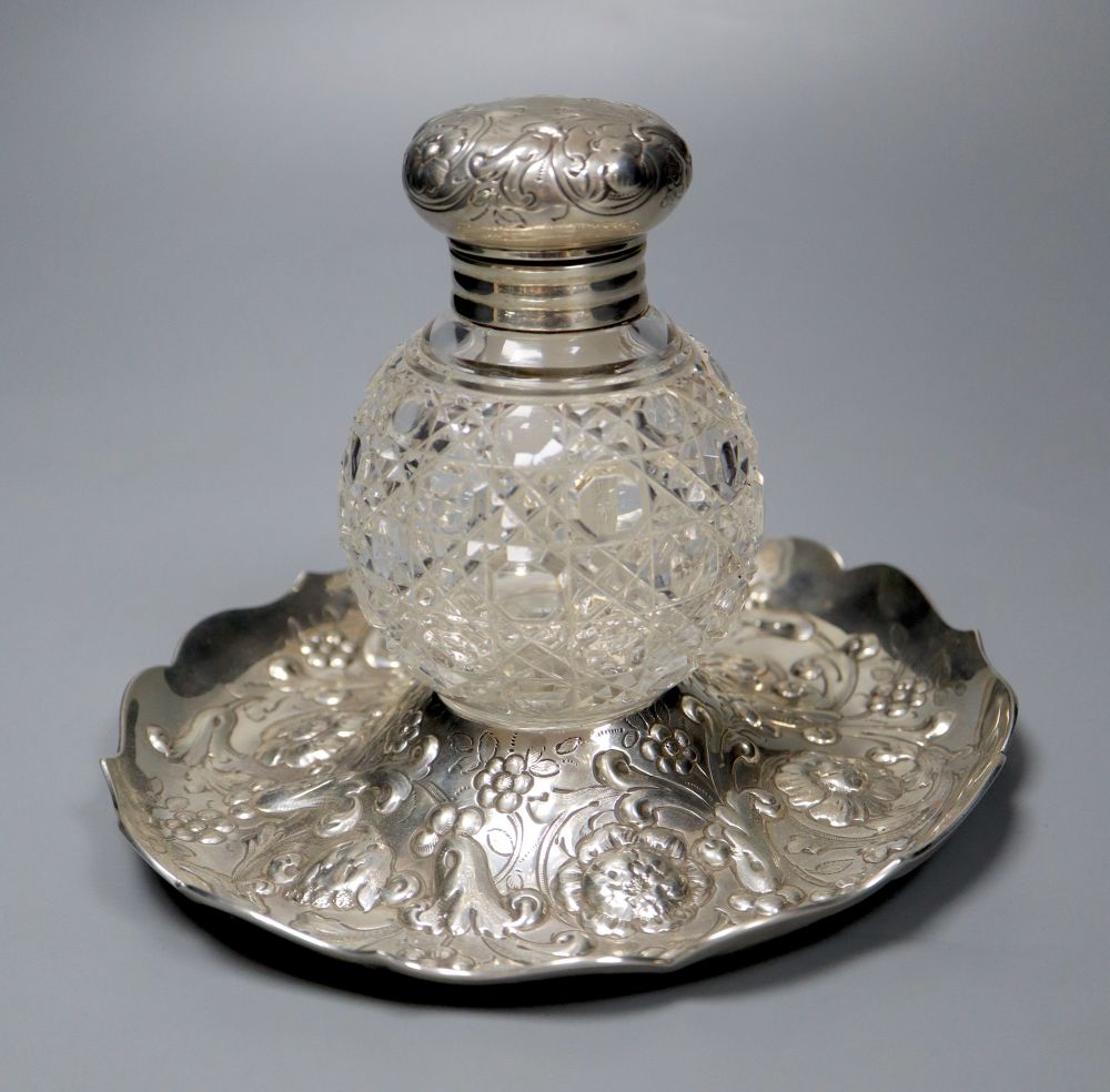 A late Victorian repousse silver mounted glass inkwell, on a repousse silver stand, London, 1891,