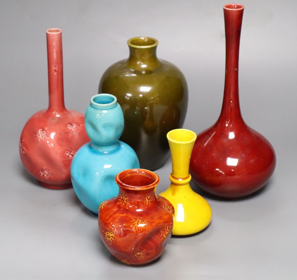 A collection of Burmantofts faience pottery vases, comprising a dark pink ground bottle-shaped