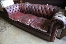 A three seater Chesterfield settee covered in deep-buttoned burgundy hide, length 210cm, depth 90cm,