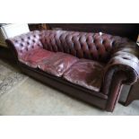 A three seater Chesterfield settee covered in deep-buttoned burgundy hide, length 210cm, depth 90cm,