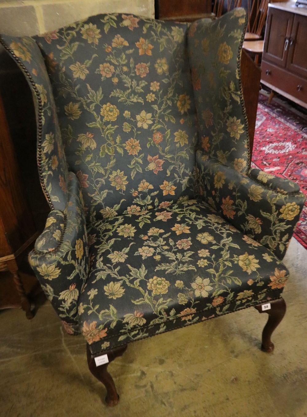 A George I style mahogany framed wing armchairCONDITION: Fading and wear to the upholstery,