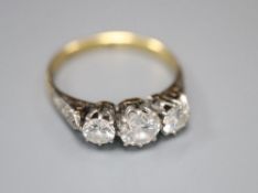 A mid 20th century '18ct and plat' three stone diamond ring, with diamond set shoulders, size K/L,