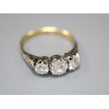 A mid 20th century '18ct and plat' three stone diamond ring, with diamond set shoulders, size K/L,