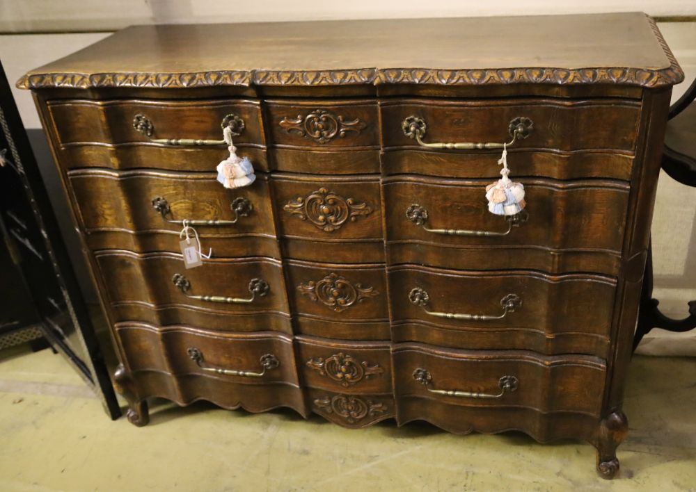 A 20th century French oak commode, fitted four long drawers with carved decoration, width 122cm,